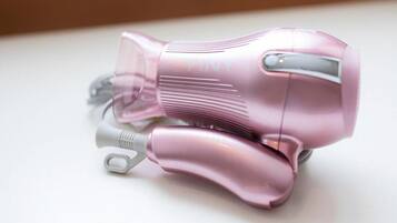 A pink hairdryer on a white surface.