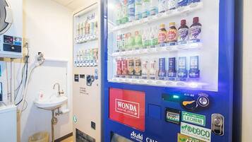 A vending machine with various beverages and a Wonda coffee label in a restroom.