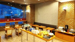 A restaurant with wooden tables and chairs, a buffet counter with food and condiments, and a view of the street outside. - Hotel Axia Inn Kushiro (Kushiro)