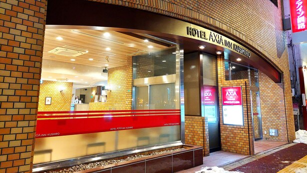 A hotel entrance with a brick facade, large glass windows, and a sign reading "HOTEL AXIA INN KUSHIRO". - Hotel Axia Inn Kushiro (Kushiro)