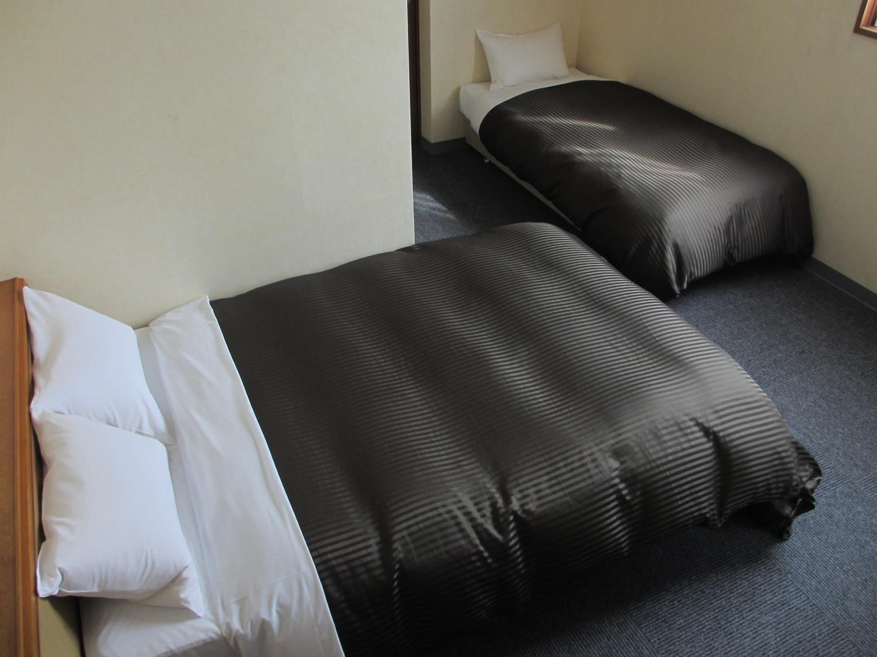 A small, compact room with two single beds, each with a black and white striped bedspread.