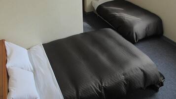 Quarto pequeno e compacto com duas camas de solteiro, cada uma com colcha listrada em preto e branco.