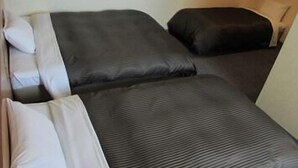 A small, compact room with two beds, each with a pillow and a blanket. - Hotel Axia Inn Kushiro (Kushiro)