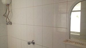 A tiled bathroom with a shower, a toilet, and a sink. - Milan Guest House (Mumbai)