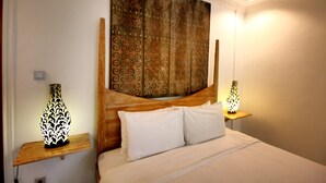 Une chambre à coucher avec une tête de lit en bois, deux tables de chevet ornées de lampes décoratives et une grande tapisserie accrochée au mur.