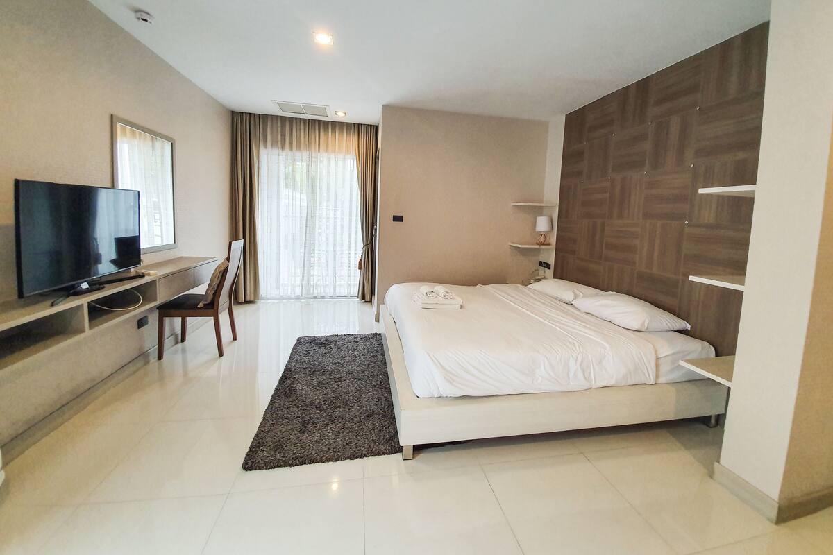 Una habitación de hotel moderna con una cama, un televisor, un escritorio y una silla.