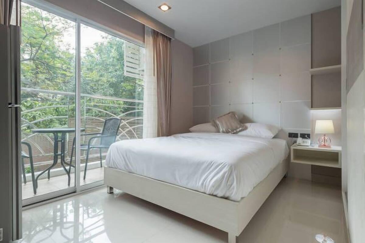 Un dormitorio con cama, mesita de noche y vista al exterior a través de una puerta corrediza de vidrio.