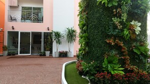 A building with a glass entrance, potted plants, and a green wall. - Parkview Ratchaprarop (Bangkok)