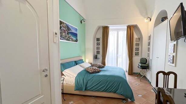 Una camera da letto con un letto, una sedia, un tavolo e una televisione.