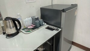 Una kitchenette con hervidor, microondas, refrigerador y una bandeja con alimentos.