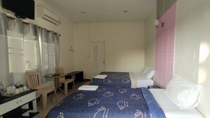 Habitación de hotel con dos camas, un escritorio, una silla, una mesita y un televisor.