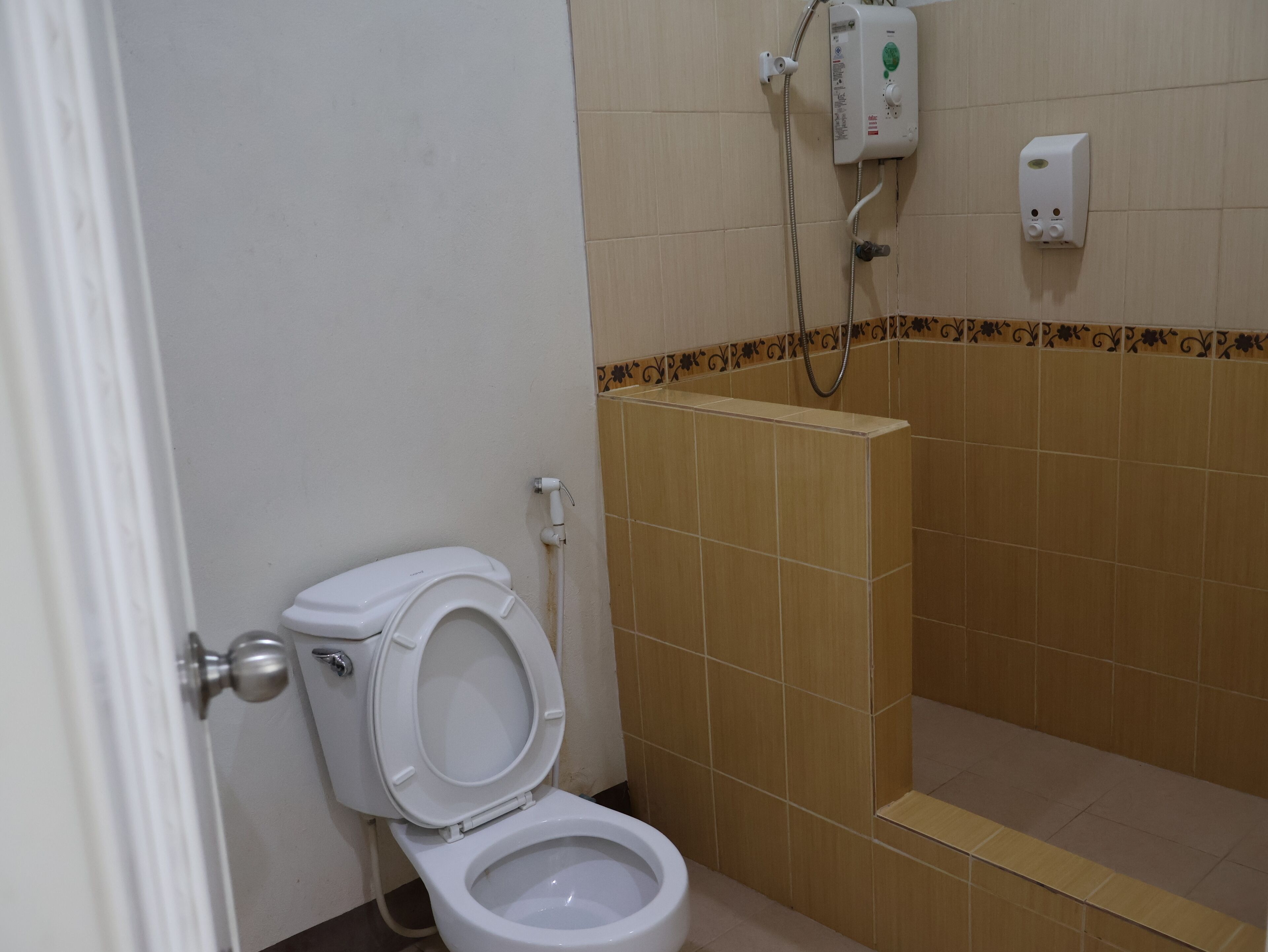 A bathroom with a toilet, a shower, and a hand dryer.