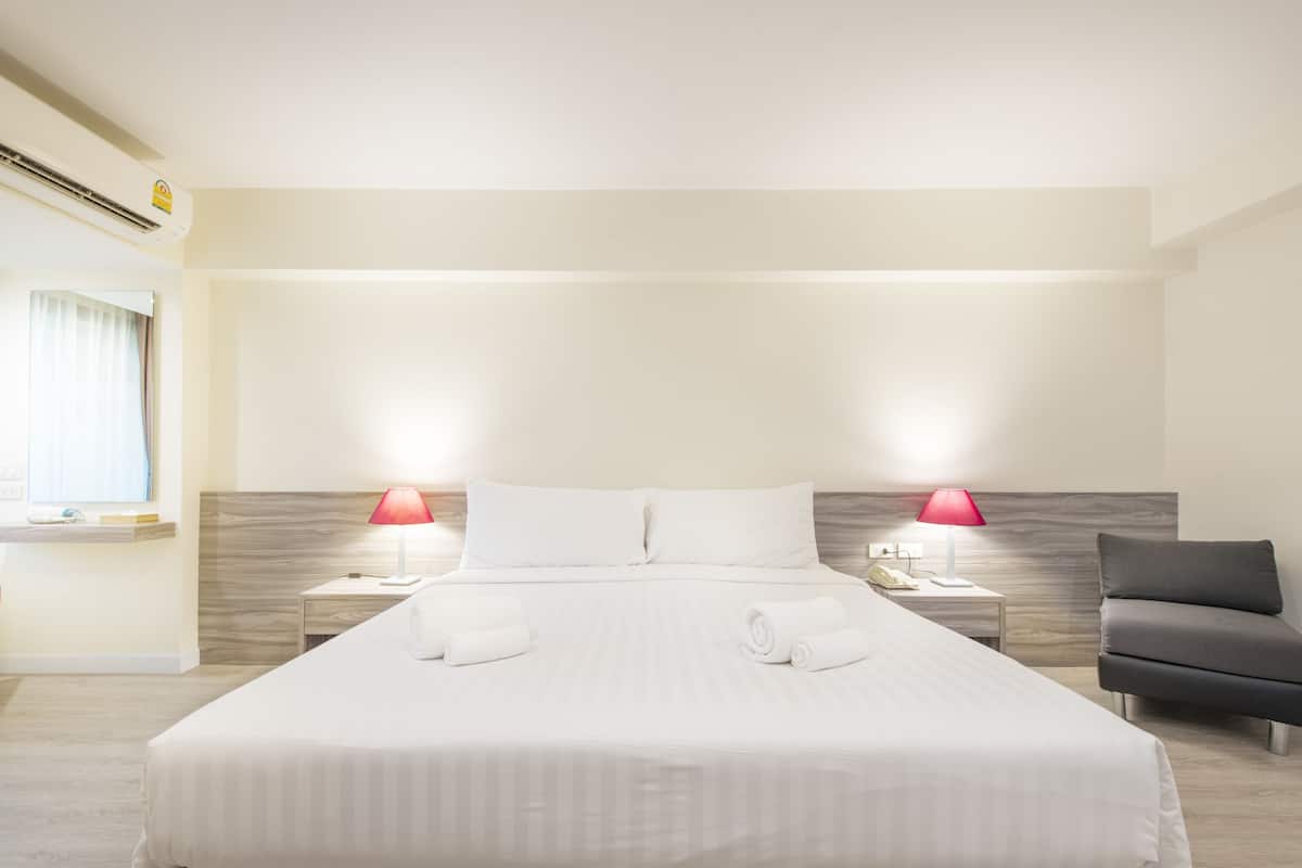 A hotel room with a large bed, two bedside lamps, a chair, and a nightstand with a phone.