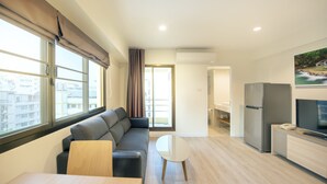 A modern living room with a sofa, a coffee table, and a TV. - Le Tada Residence (Bangkok)