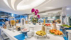 A buffet setup with various food items and a decorative orchid arrangement. - Le Tada Residence (Bangkok)