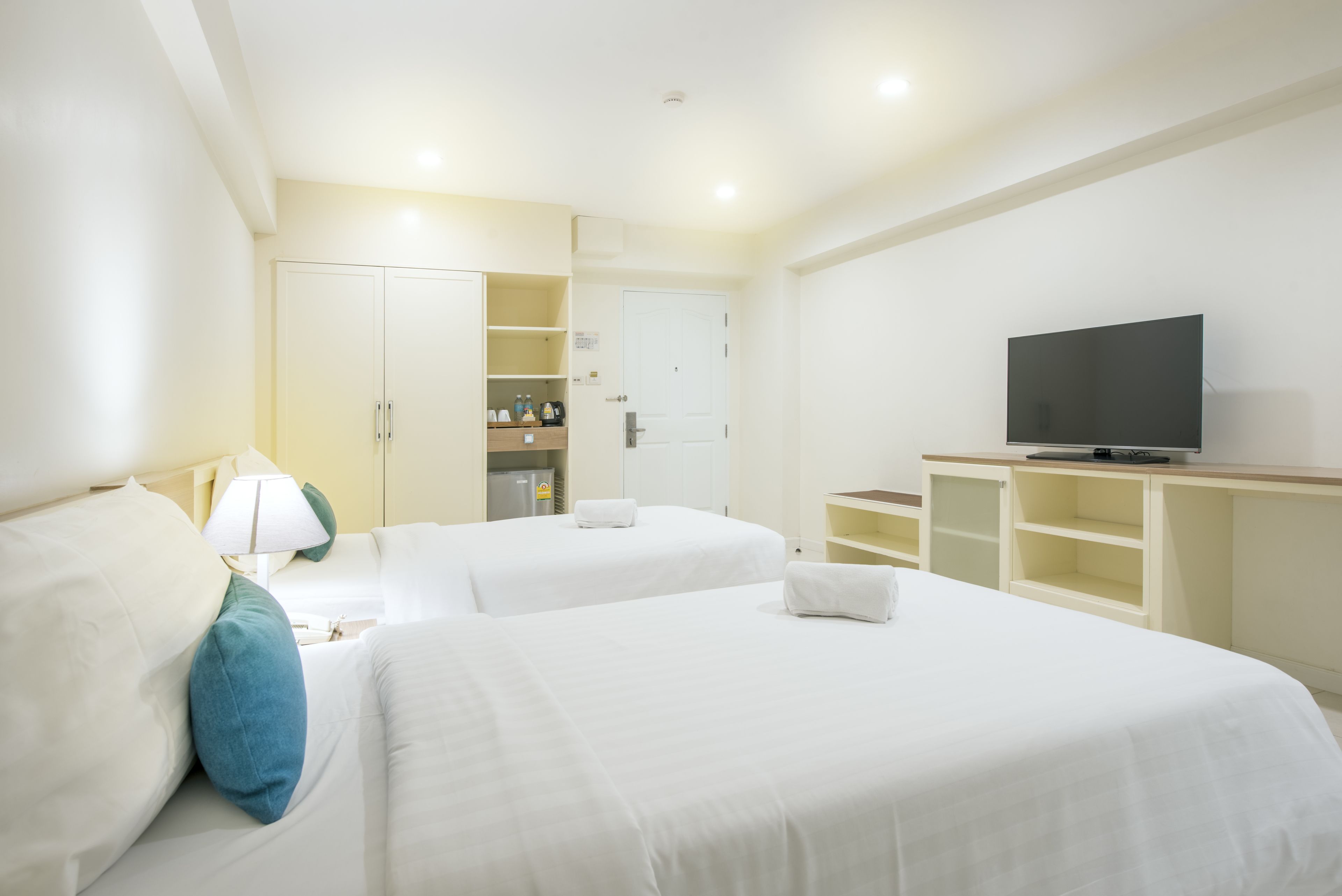 Une chambre d’hôtel avec deux lits, une télévision, une armoire et un mini-bar.