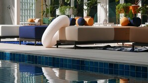 A modern poolside area with a lounge, potted plants, and a clear pool. - Le Tada Residence (Bangkok)