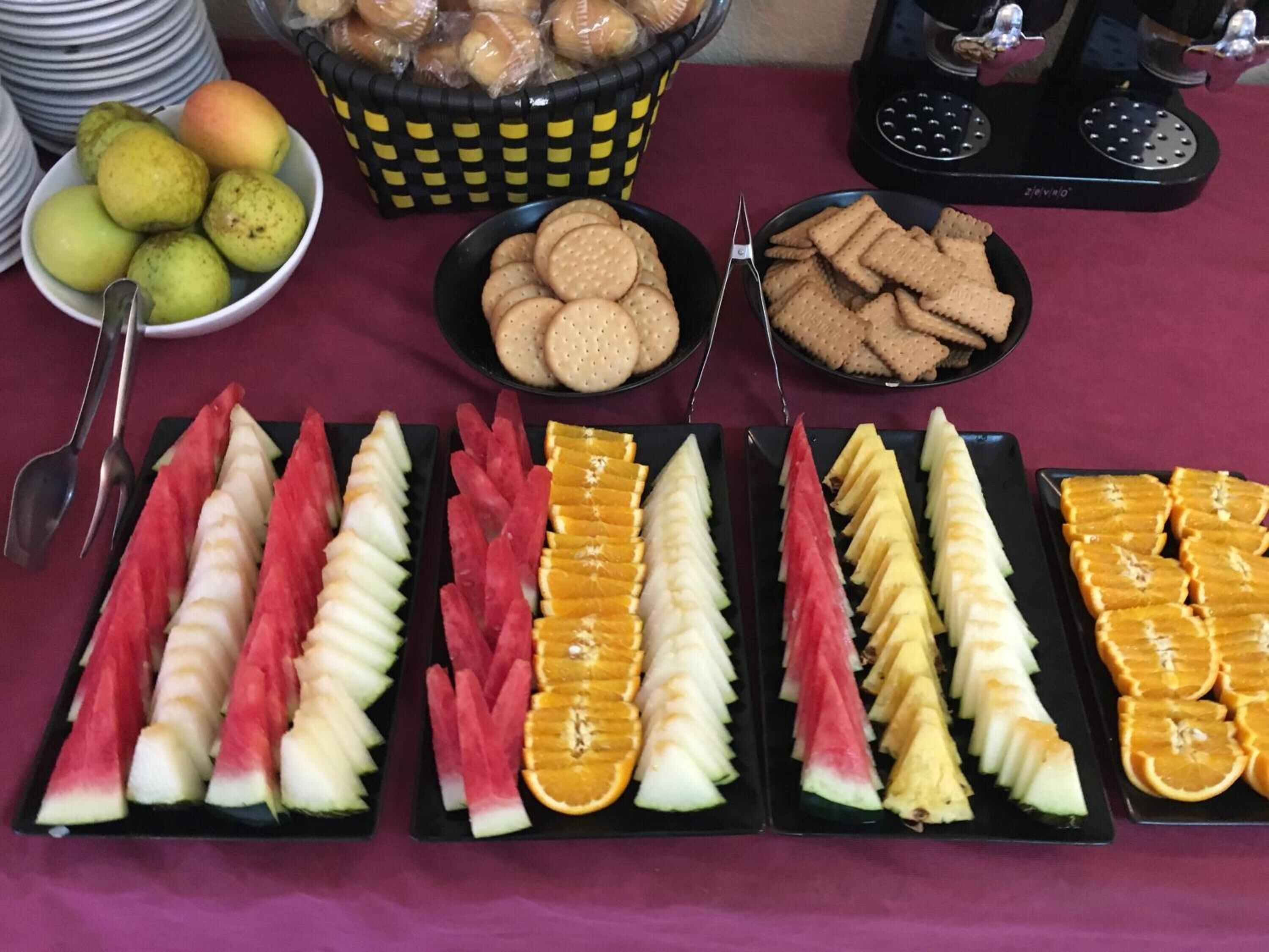 Una mesa de buffet con frutas y aperitivos varios.