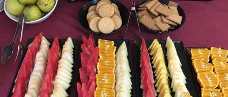 Una mesa de buffet con frutas y aperitivos varios.