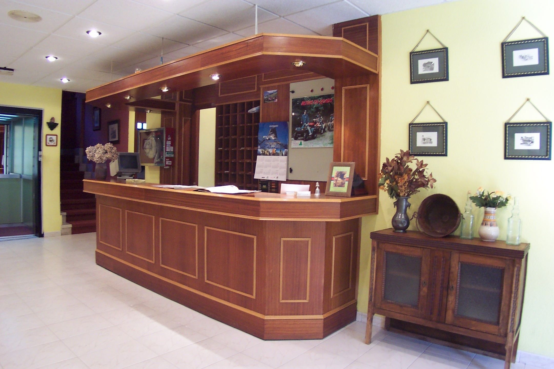 A reception desk with a wooden finish, a mirror, and framed pictures on the wall.