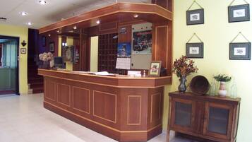 A reception desk with a wooden finish, a mirror, and framed pictures on the wall.
