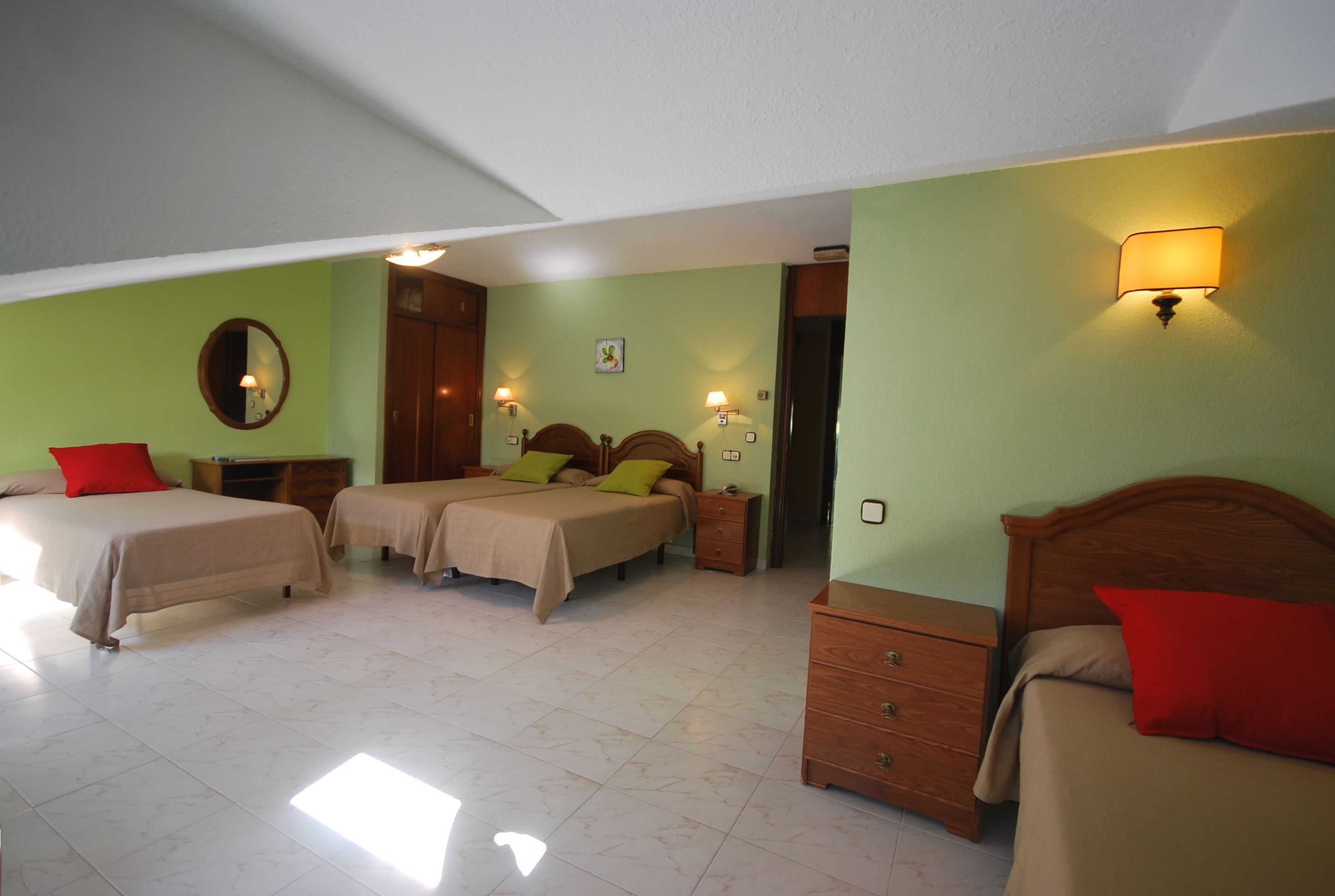 A hotel room with two beds, a wooden nightstand, a dresser, and a mirror on the wall.