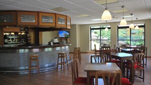 Ein Restaurant mit Barbereich, Holztischen und -stühlen.