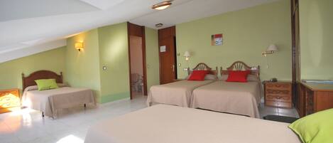 A hotel room with two single beds, a wooden dresser, a nightstand, and a bathroom visible through an open door.