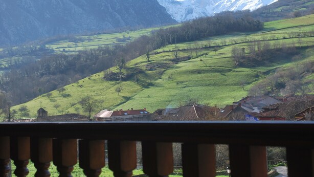 Eine Berglandschaft mit einem Dorf und Blick auf schneebedeckte Gipfel.