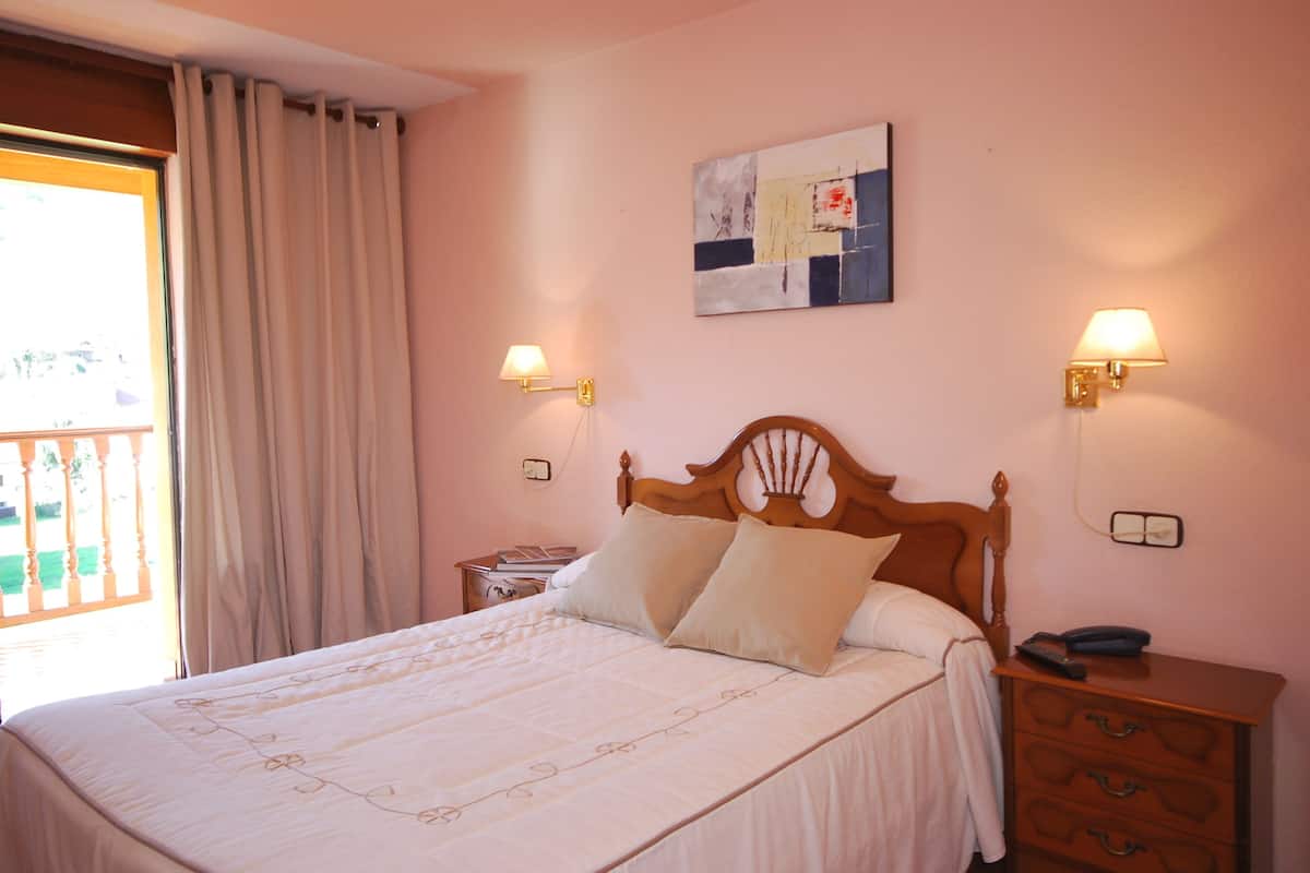 Une chambre à coucher avec un lit en bois, deux lampes de chevet, une table de chevet et une œuvre d’art accrochée au mur.