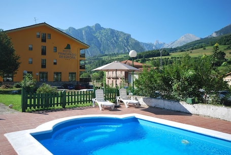 Una piscina al aire libre, sombrillas, sillones reclinables de piscina
