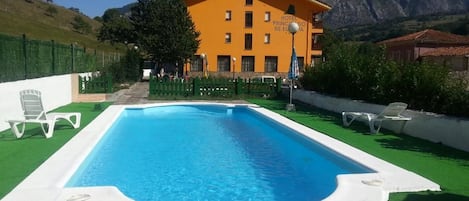 Una piscina al aire libre, sombrillas, tumbonas