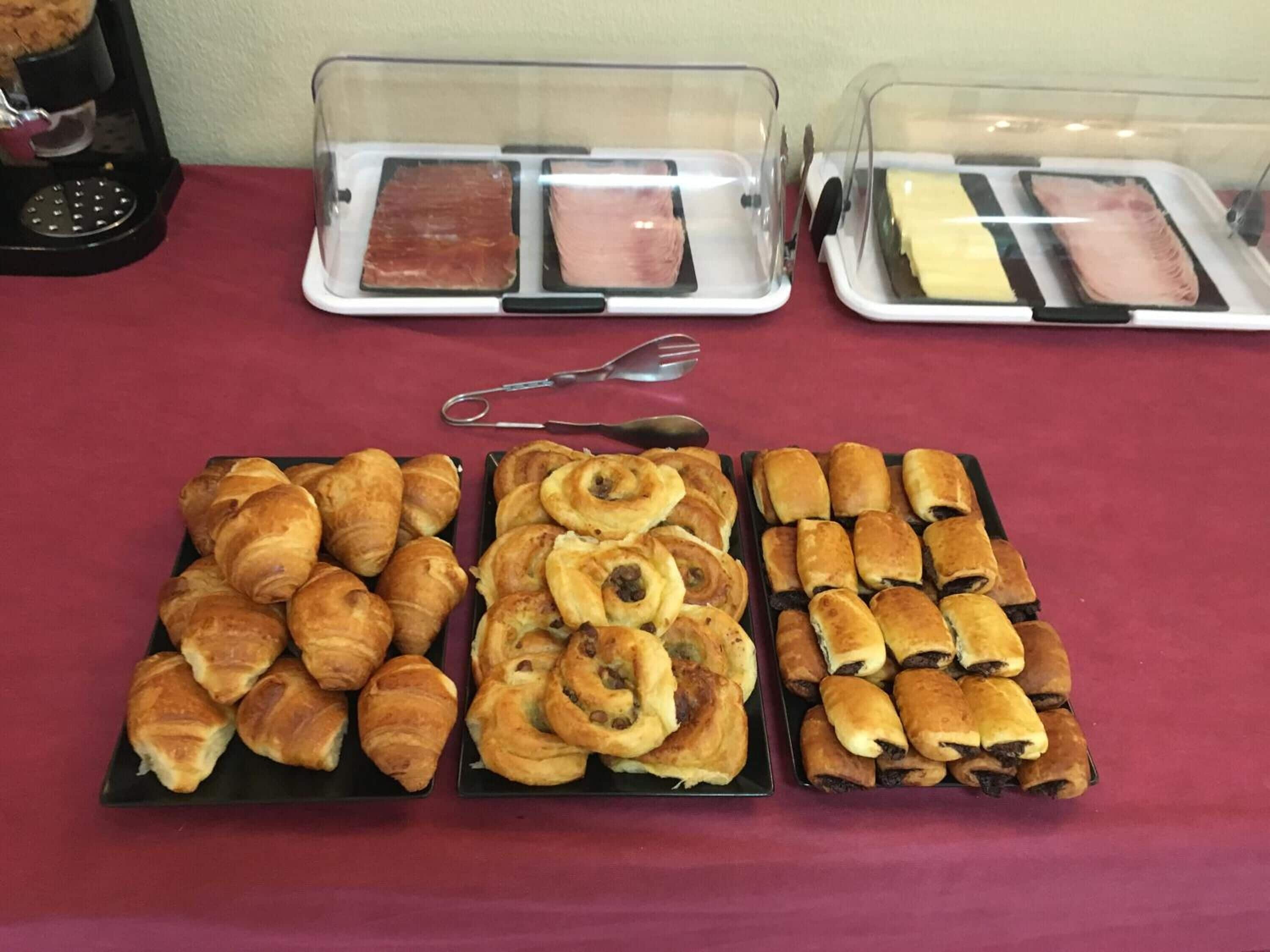 Une table de buffet proposant une variété de produits de boulangerie et de plats à base de viande.