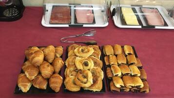 Une table de buffet proposant une variété de produits de boulangerie et de plats à base de viande.