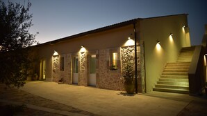 A building with a stone facade, multiple doors, and a staircase leading to an upper level. - La Mela di Venere (Palazzolo Acreide)