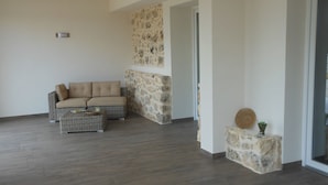 A spacious living area with a beige sofa, a wicker coffee table, and a stone accent wall. - La Mela di Venere (Palazzolo Acreide)
