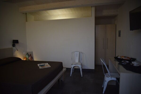 Une chambre avec un lit, un bureau, une chaise et une petite table sur laquelle se trouve de la nourriture.