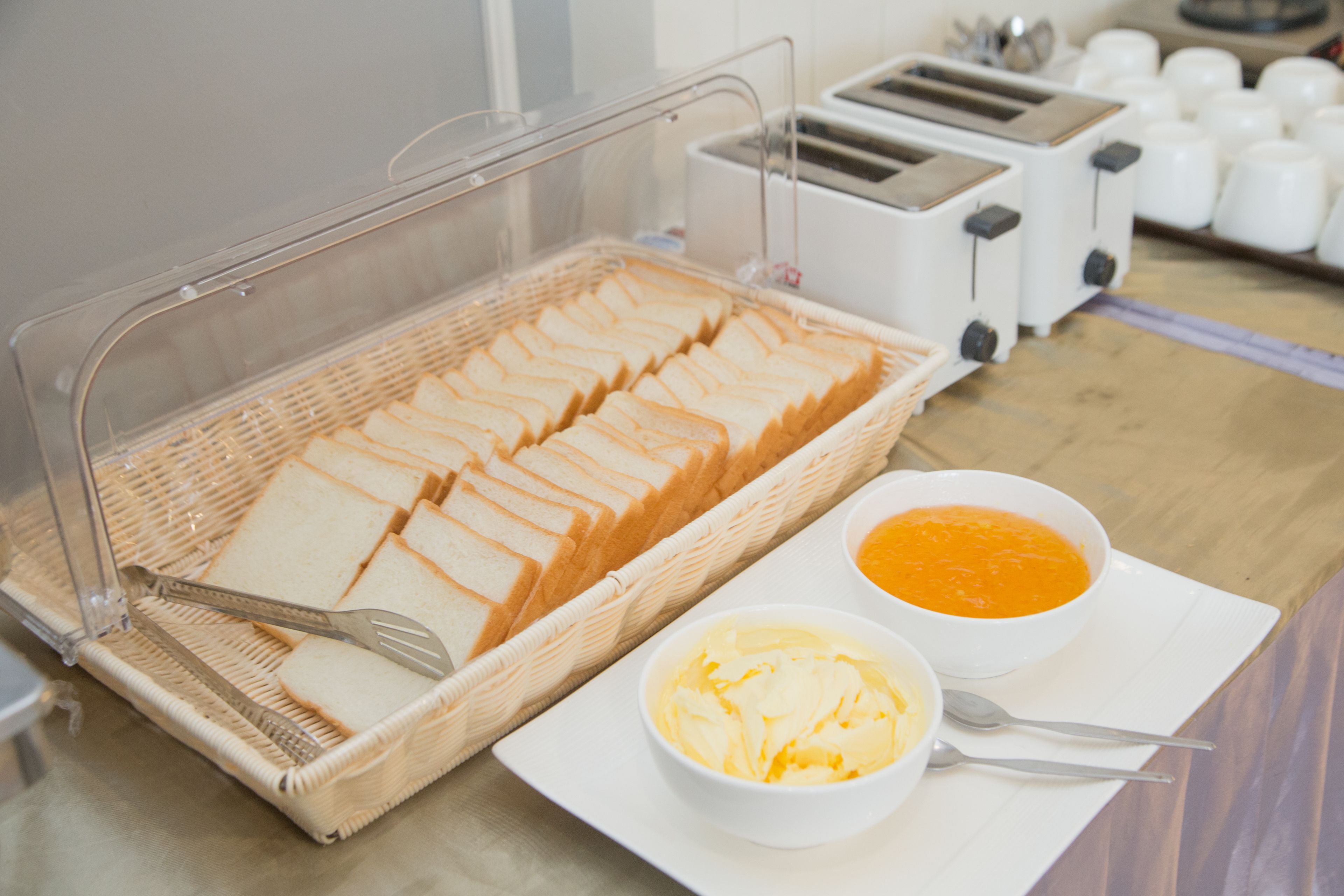Disposição de buffet com pão fatiado, manteiga e sopa.
