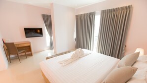 Ein Hotelzimmer mit Bett, Schreibtisch, Stuhl, Fernseher und Vorhängen.