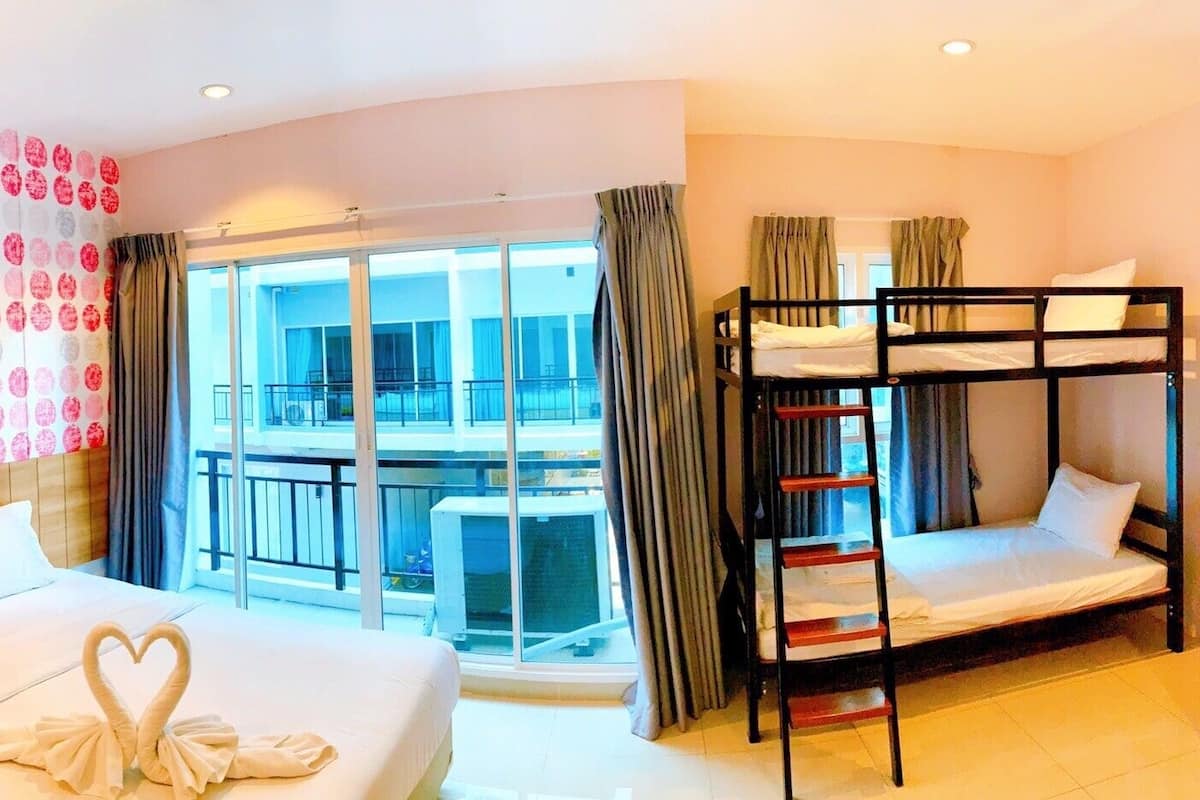 Ein Hotelzimmer mit einem großen Bett, einem Etagenbett und einem Balkon mit Blick auf die Stadt.