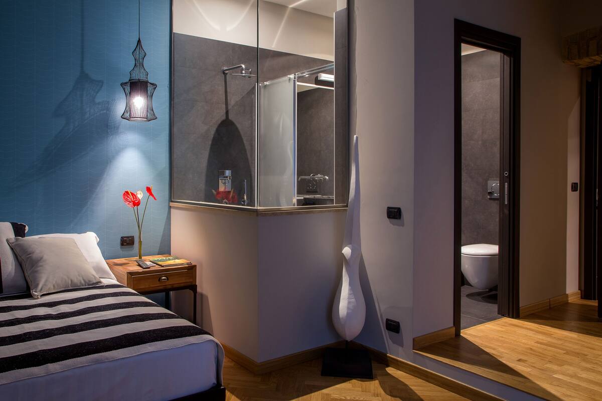 Een moderne slaapkamer met een bed, nachtkastje en spiegel.