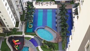 A rooftop pool area with multiple swimming pools, palm trees, and lounge chairs. - Bella Vista Apartments OnThree20 Colombo (Colombo)