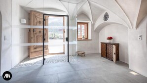 A spacious room with a large arched ceiling, a wooden cabinet, and a glass door leading to an outdoor area.