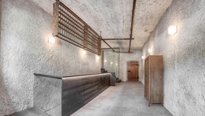 A hallway with a reception desk, a wooden door, and a textured wall.