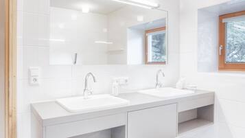 Ein modernes Badezimmer mit zwei Waschbecken, einem großen Spiegel und einem Fenster mit Aussicht.