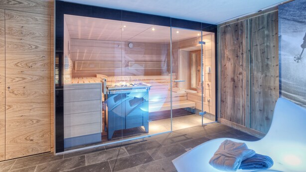 A modern bathroom with a glass-enclosed shower area, wooden paneling, and a large mirror.