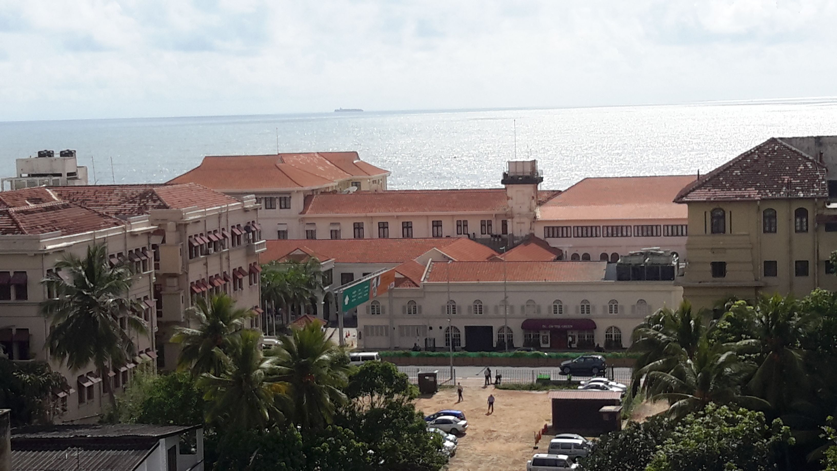 Un pueblo costero con edificios de tejados rojos y un edificio blanco destacado con toldo verde.