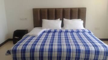Una cama con colcha azul y blanca a cuadros, dos almohadas blancas y un cabecero tapizado en marrón.