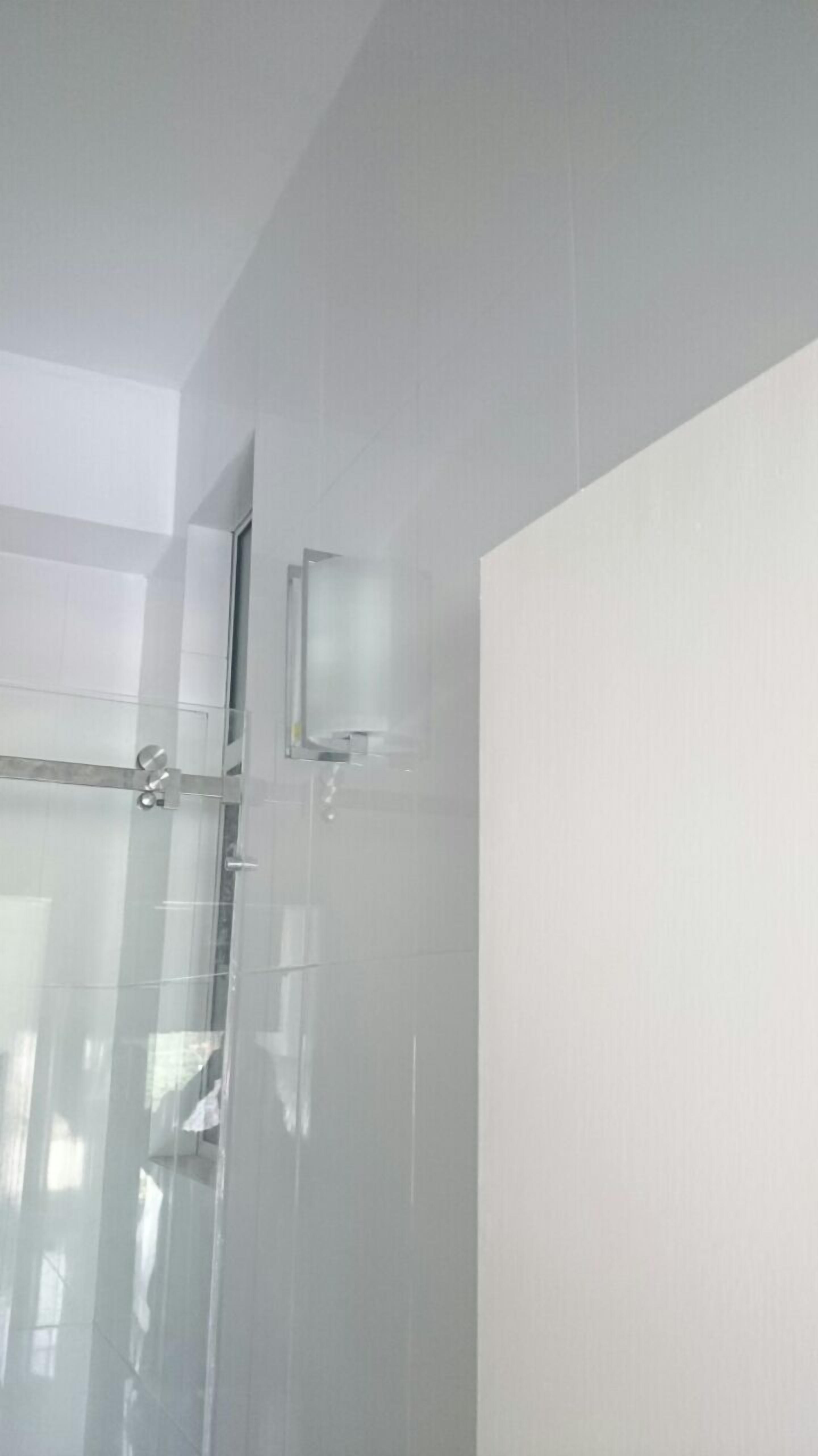 Un baño moderno con cabina de ducha de vidrio, un cabezal de ducha visible y un panel de control en la pared.
