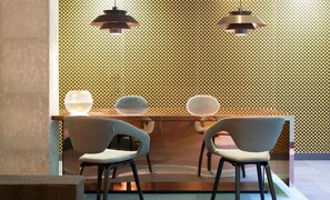 A modern interior with a patterned wall, two pendant lights, and two chairs with a glass table. - Be Mate Málaga Soho (Málaga)